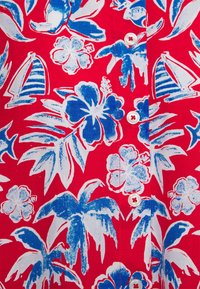 Tessuto rosso con un motivo floreale che presenta fiori blu e foglie di palma, con motivi di velieri bianchi come accento, e bottoni bianchi lungo il centro.