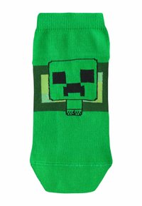 Chaussette vert vif présentant un visage pixellisé de Creeper de Minecraft centré sous le bord-côte.