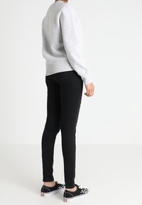 Šedá mikina, černé úzké džíny a černé tenisky. Džíny mají na boku žebrované detaily. Jednoduchý a neformální outfit.