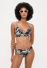 Floral bikini-set med svart bakgrunn, trekantet bralette-design, tynne stropper og matchende lave truser med bladmønster.