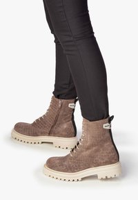 Bottines brunes texturées avec un motif crocodile, design à lacets, semelle en caoutchouc beige et une fermeture éclair sur le côté pour un enfilage facile.