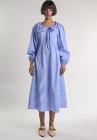 Abito a maniche lunghe a righe blu e bianche con scollatura arricciata e dettaglio fiocco. Tessuto liscio con maniche a sbuffo e vestibilità rilassata.