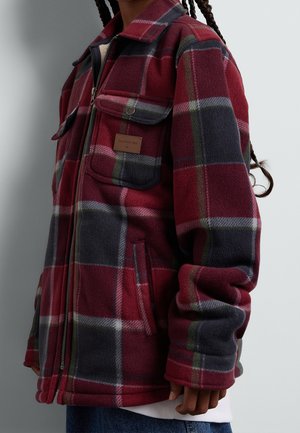 Rød og grå ternet fleecejakke med to forlommer og lynlåslukning, med et mærket læderpatch på brystlommen.