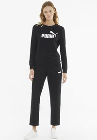 Melns sporta krekls un bikses ar baltu "PUMA" logotipu, mīksts audums, garas piedurknes un taisna piegriezuma bikses ar elastīgu jostasvietu.
