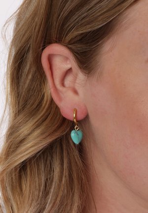 Gouden oorbel met een turquoise hart hanger. De steen heeft een gladde afwerking en subtiele aders, hangend aan een veilige sluiting.