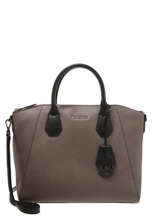 Sac à main en cuir texturé taupe avec anses noires, bandoulière amovible et un pendentif logo rond noir suspendu à l'avant.