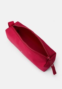 Trousse en tissu rouge avec une ouverture zippée, de forme rectangulaire, surface texturée et une petite boucle sur le côté pour un transport facile.