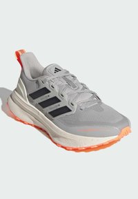 Grå løbesko med sorte striber, tekstureret mesh-overdel, polstret krave og orange sål-accente. Har vandtæt materiale.