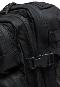 Juodas taktinis kuprinės, turinčios kelis užtrauktukus, tekstūruotą nailoną, reguliuojamus diržus ir plastiką užsegimą.
