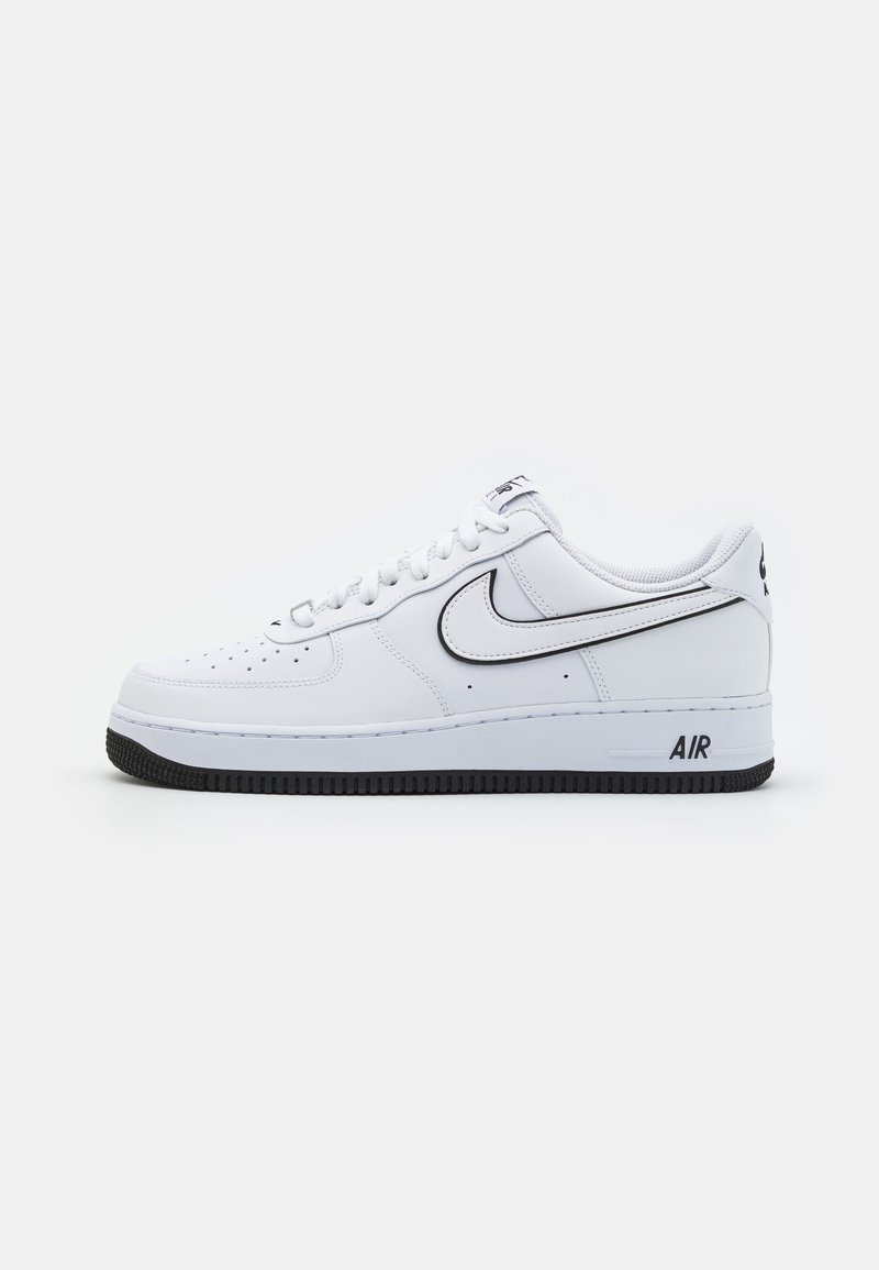 Fehér bőr sportcipők alacsony toppal, fekete gumitalppal, perforált orral és fekete keretes Nike swoosh logóval.