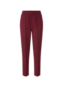 Pantalons de jogging bordeaux avec une taille élastique, un cordon de serrage et des poches latérales. Texture lisse, jambes fuselées et design minimaliste.