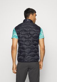 Jūras flotes krāsas pūkains bezpiedurkņu mētelis ar augstu apkakli, kas rotāts ar kvadrāta šuvēm. Valkāts virs tirkīza grafiskās krekla. Gluda, viegla auduma.