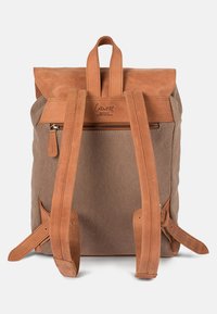 Brown canvas backpack with tan leather accents, a flap closure, and adjustable straps; features a zippered pocket on the back.