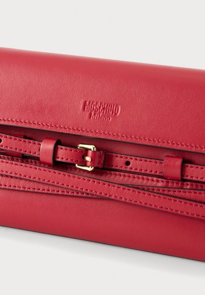 Κόκκινο δερμάτινο clutch Moschino Milano με λεπτό λουράκι και μικρή χρυσή αγκράφα σε απλό φόντο.