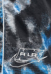 Ύφασμα με μαύρο, μπλε και λευκό μοτίβο, με λευκό κεντημένο λογότυπο Nike Air 5 και έμβλημα swoosh στην επιφάνεια.