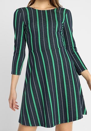 Marineblå og grønstribet kjole med trekvartærmer, en tætsiddende liv og en flagrende nederdel. Stoffet ser blødt og struktureret ud.