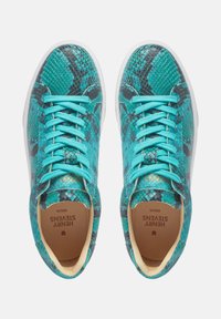 High-Top Sneakers mit einem türkisfarbenen und schwarzen Schlangenledermuster, flachen tealfarbigen Schnürsenkeln, weißen Gummisohlen und einer beigen Innenauskleidung.