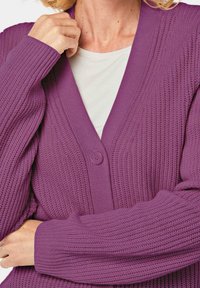 Lila Strickjacke mit einem strukturierten Strickmuster, V-Ausschnitt und einem einzelnen Knopfverschluss. Lange Ärmel mit gerippten Bündchen.