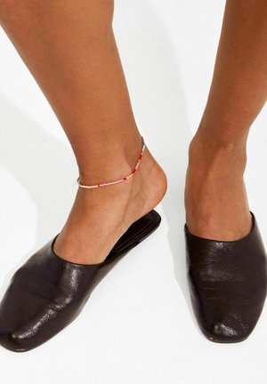 Mustad nahast libisevad kingad terava varbapoolse otsikuga, mida on kombineeritud mitmevärvilise helmestega pahkluu ehtimisega. Sile tekstuur, minimalistlik disain.