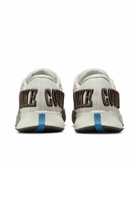 Weiße Sneaker mit brauner "COWAKE" Schrift, grauem Mesh-Fersenbereich und blauen Akzenten an der Sohle. Strukturmaterial mit runder Form.