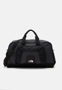 Black duffel bag with a smooth fabric, mesh pocket, dual carrying handles, and adjustable strap. Features logo on the front panel.