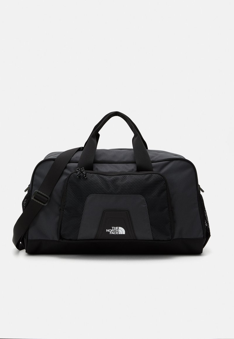 Black duffel bag with a smooth fabric, mesh pocket, dual carrying handles, and adjustable strap. Features logo on the front panel.