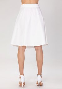 Jupe évasée blanche avec une taille haute, confectionnée en tissu lisse, présentant un ourlet au genou et des plis subtils pour une texture ajoutée.