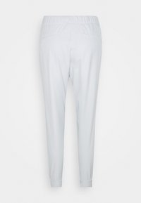 Ljusgrå joggerbyxor med elastisk midja, åtsittande fållar och två bakfickor; slät textur med en enkel design.