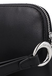 Pochette in pelle nera con finitura testurizzata, accessori in tonalità argento e un dettaglio con logo circolare. Presenta una chiusura con zip e una tracolla removibile.