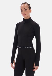 Juodas sportinis švarkas su aukštu apykakle, priekiniais užtrauktukais ir ilgomis rankovėmis. Logo juosta liemenyje, sklandžiai prisitaikanti medžiaga.