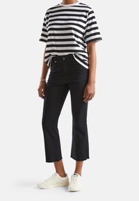 Svartvitrandig t-shirt med avslappnad passform, kombinerad med högmidjade svarta korta jeans och vita sneakers. Enkel design, avslappnad stil.