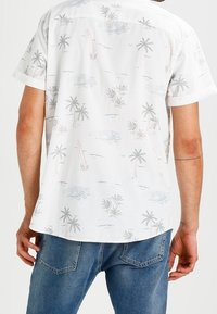 Kurzärmliges weißes Hemd mit einem Muster aus Palmen und Surfbrettern. Leichter Stoff, lässige Passform und Design mit Knopfleiste am Kragen.