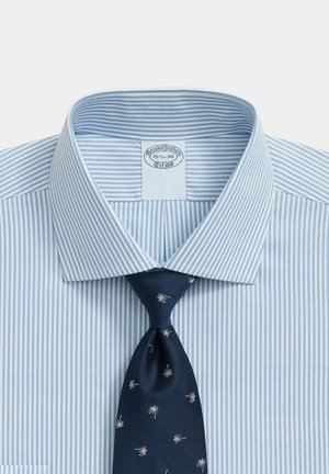 Lichtblauw-wit gestreept overhemd met een donkerblauwe stropdas met kleine witte sterpatronen, kraag open en netjes gevouwen.