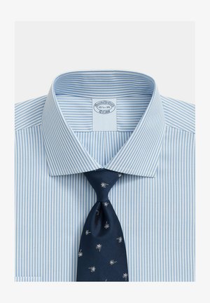 Lichtblauw-wit gestreept overhemd met een donkerblauwe stropdas met kleine witte sterpatronen, kraag open en netjes gevouwen.