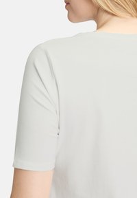 Lys grå t-shirt med rund halsudskæring og korte ærmer, lavet af blød bomuld, med en glat tekstur og et enkelt design.