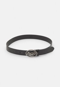 Zwarte leren riem met een gestructureerd oppervlak en een ovale zilverkleurige gesp met een gestileerd logo. Meerdere verstelgaten inbegrepen.