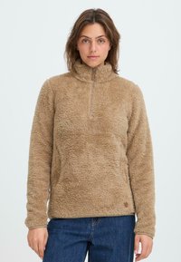 Brauner Fleece-Pullover mit hohem Kragen, halbem Reißverschluss und Fronttaschen. Weiche Textur mit einem leicht gebürsteten Finish und genähten Details.