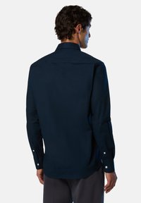 Camisa de manga larga azul marino con cuello puntiagudo, puños con botones y una textura suave. La vista trasera muestra un diseño limpio sin patrones.