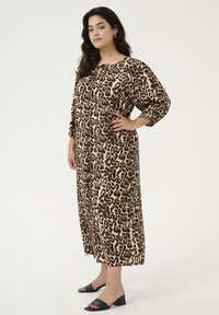 Vestido largo y holgado de estampado de leopardo en tejido suave; cuenta con un cuello redondo y mangas tres cuartos. Llevado con mocasines negros de tacón.