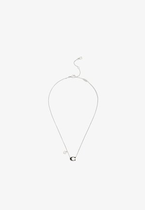 Collana con catena in argento con un ciondolo a forma di "C" nero e argento e un piccolo charm a forma di cuore vicino alla chiusura su sfondo bianco.