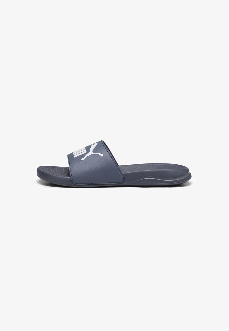 Sandale slide bleu marine avec semelle anatomique et logo Puma blanc sur une large bride, vue de profil sur fond blanc.