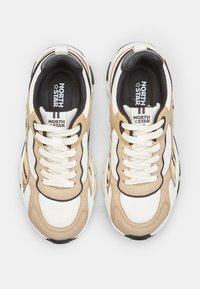 Par de zapatillas North Star beige y blancas con detalles en negro, cordones blancos y plantillas con la marca, vistas desde arriba sobre un fondo blanco.