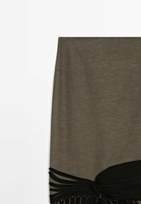 Tissu vert olive avec une section de tissu noir froncé et plusieurs bandes de frange noire s'étendant depuis le bord inférieur.