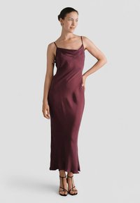 Bordowa satynowa sukienka na ramiączkach, z dekoltem w kształcie łezki oraz swobodną sylwetką, zakończona lekko rozszerzanym dołem.