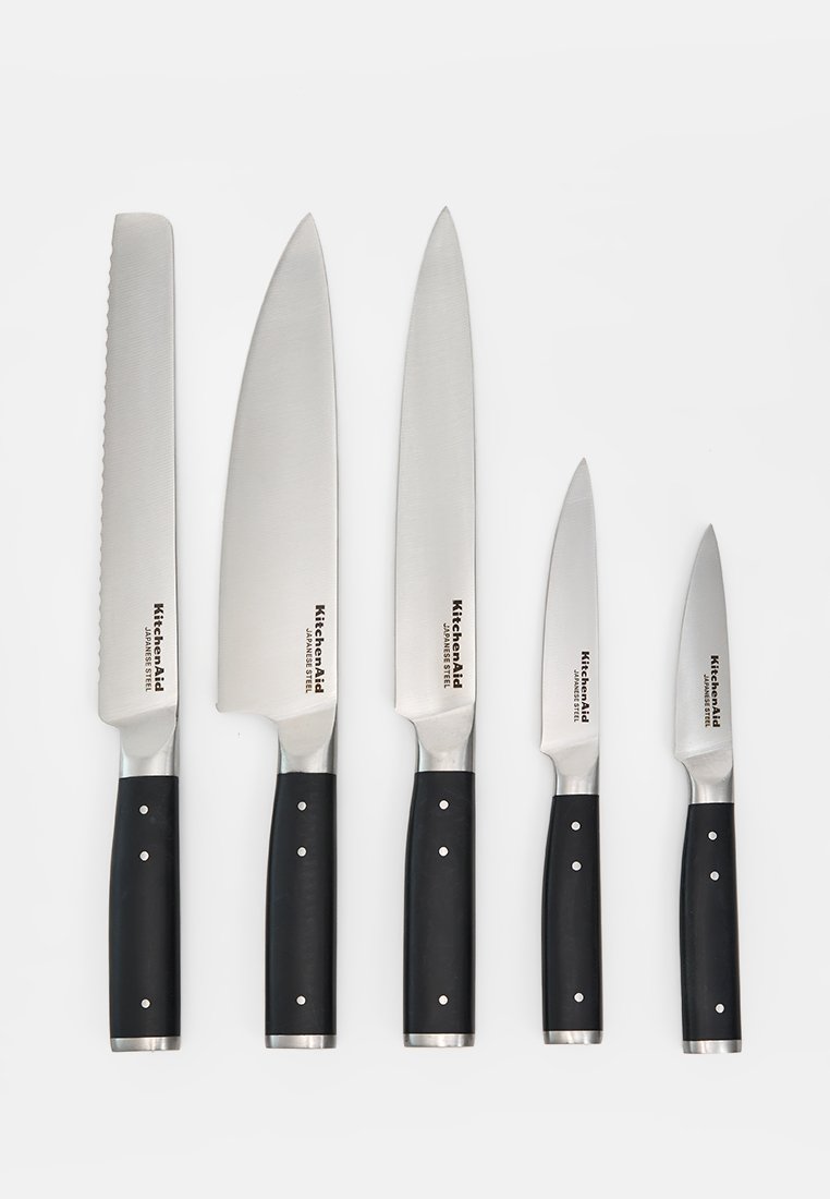 Cinq couteaux de cuisine KitchenAid en acier japonais avec manches noirs, disposés par taille sur un fond blanc.