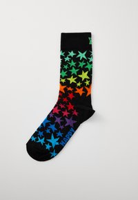 Black socks with a gradient of colorful star patterns in green, orange, red, and blue. Features "HAPPY" text in blue at the toe.