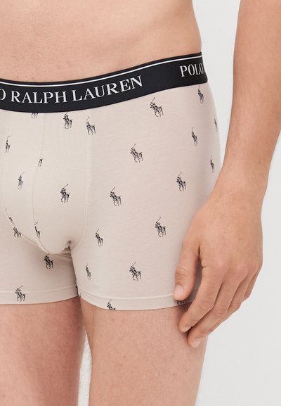 Boxers Ralph Lauren em bege com uma faixa preta; apresentam um padrão de logótipos repetidos em preto. Material macio e elástico.