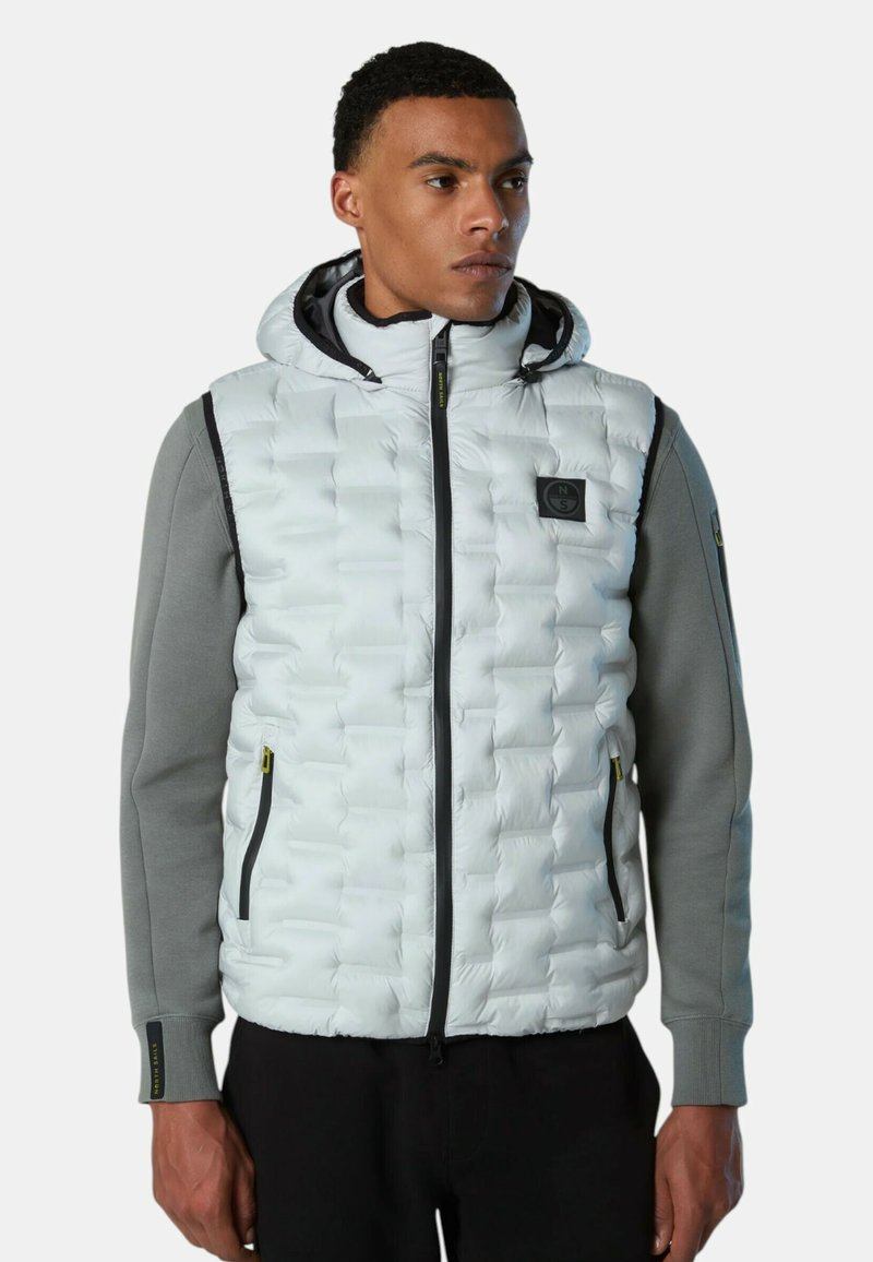 Gepolsterte Weste in Hellgrau mit Kapuze, ausgestattet mit einem gesteppten Design, grauen Ärmeln, schwarzen Reißverschlüssen und einem Logo auf der Brust.