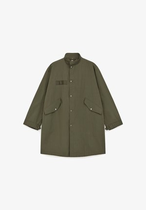 Olijfgroene jas gemaakt van lichtgewicht stof, met een opstaande kraag, drukknoopsluiting en twee klepzakken aan de voorkant. Strak en minimalistisch ontwerp.