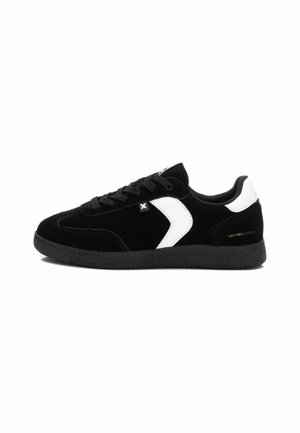 Zapatillas negras de ante con un diseño de acento blanco. Cuenta con cordones y una suela de goma texturizada negra. Estilo minimalista con un detalle de marca en dorado.
